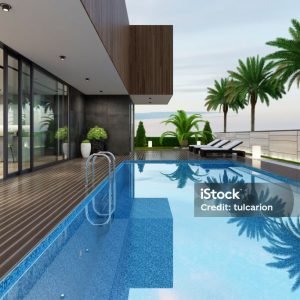 Luxurious villa with outside swimming pool at summer scene.
Big blue swimming pool near living room and kitchen. 
Stylish and comfortable sun area with a modern brown sunbeds. 
Dark gray accent slate stone walls with natural plants.
Natural floor tiles. Ceiling with white spotlights.

+++ background is my photo.